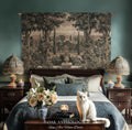May include: A wall tapestry featuring a landscape scene with trees and a garden, hung above a bed with two lamps, a bouquet of roses and lilies in a blue and white vase, and a white cat. The text OAK ANTHOLOGY Fine Art Home Decor is visible.